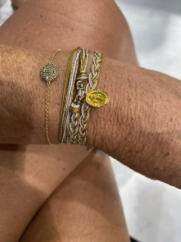 Poignet orné de plusieurs bracelets en or et tressés.